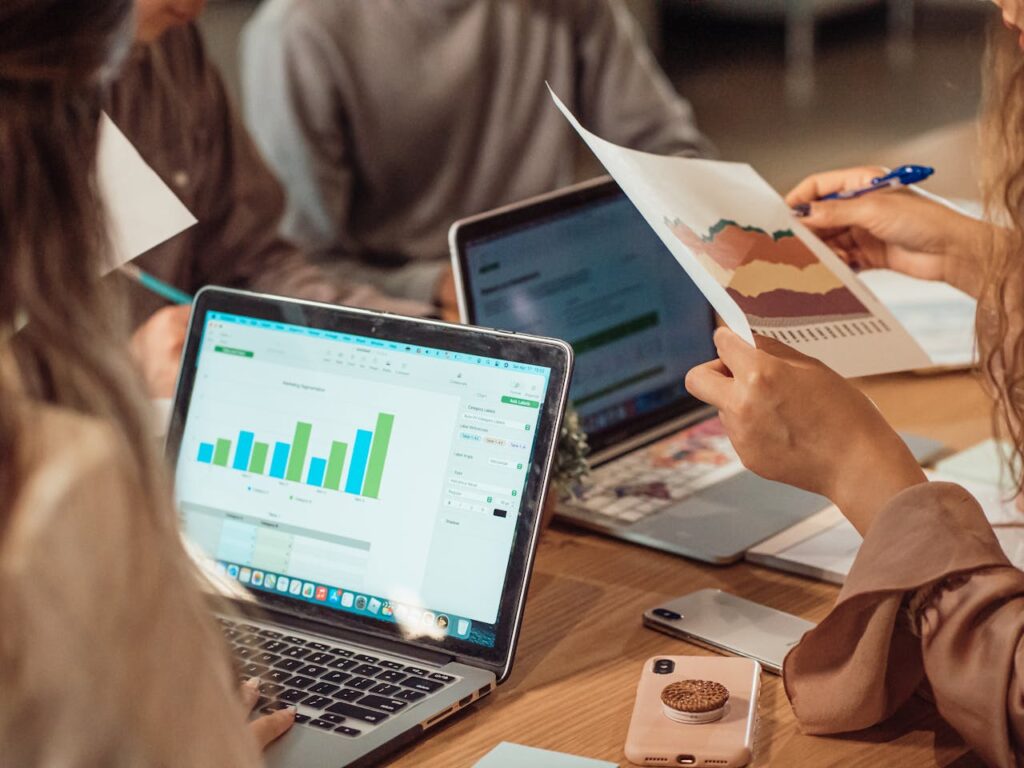 pexels photo 7651734 A group engaged in a business meeting analyzing charts on laptops and papers.