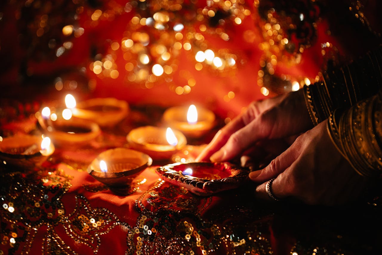 gallery-3 Hands lighting candles during a vibrant Indian festival ceremony.